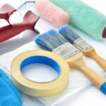 21802488 - painting tools on white background  paint rollers, brushes, drop cloth, masking tape and gloves